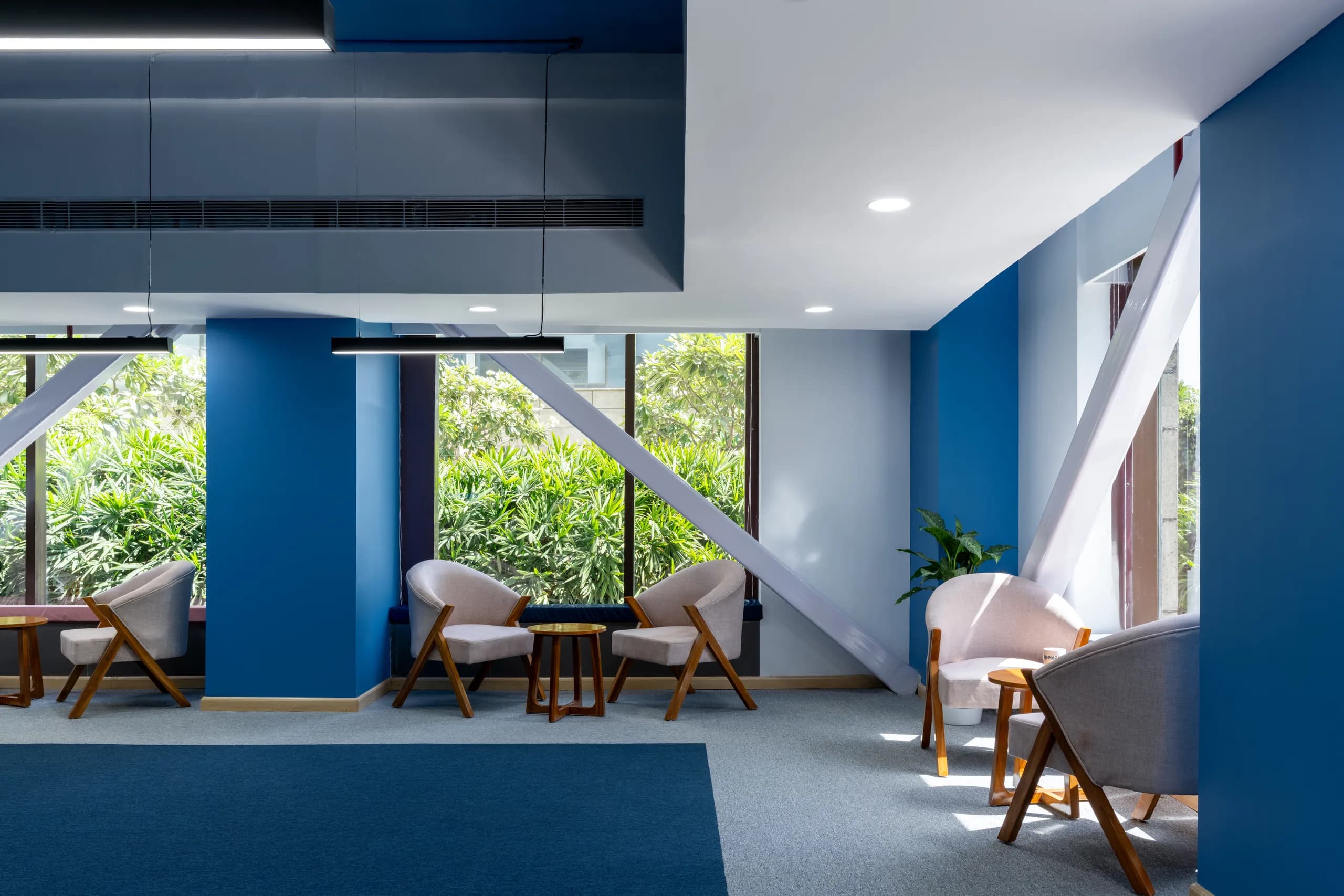Breakout lounge with blue columns, a diagonal brace and a garden view, Blue Grid Workspace